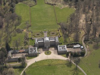 Oblique aerial view centred on the country house with the stable block adjacent, taken from the NNW.