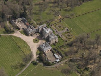 Oblique aerial view centred on the country house with the stable block adjacent, taken from the W.
