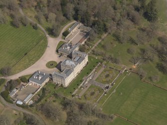 Oblique aerial view centred on the country house with the stable block adjacent, taken from the SW.