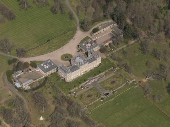 Oblique aerial view centred on the country house with the stable block adjacent, taken from the SSW.