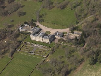 Oblique aerial view centred on the country house with the stable block adjacent, taken from the SE.