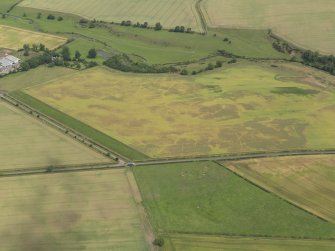 Oblique aerial view of the cropmarks of the barrow, unenclosed round houses, pits and rig, taken from the SW.