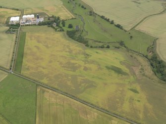 Oblique aerial view of the cropmarks of the barrow, unenclosed round houses, pits and rig, taken from the SSE.