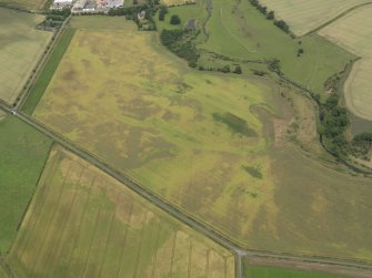 Oblique aerial view of the cropmarks of the barrow, unenclosed round houses, pits and rig, taken from the SE.