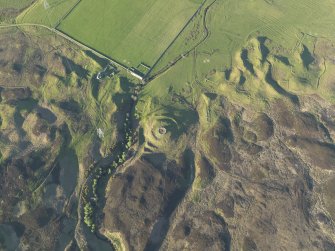 Oblique aerial view of the remains of the broch, township buildings, rig and hut-circle at Kilbraur, taken from the SW.