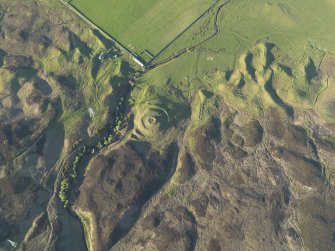 Oblique aerial view of the remains of the broch, township buildings, rig and hut-circle at Kilbraur, taken from the SW.