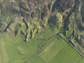 Oblique aerial view of the remains of the broch, township buildings, rig and hut-circle at Kilbraur, taken from the NE.