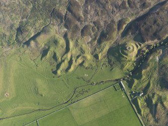 Oblique aerial view of the remains of the broch, township buildings, rig and hut-circle at Kilbraur, taken from the NNE.