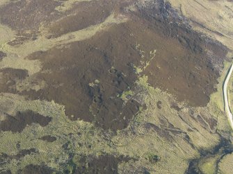 Oblique aerial view of the remains of the hut-circles and small cairns, taken from the SSW.