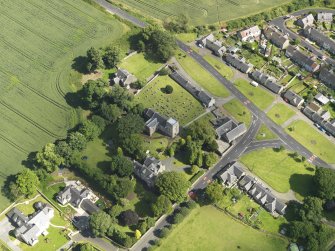 Oblique aerial view of Dalmeny centred on St Cuthbert's Church, taken from the NW.