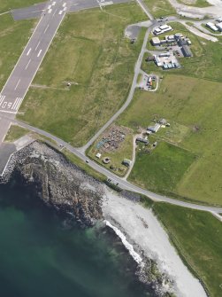 Oblique aerial view centred on the excavated broch and settlement at Old Scatness, Sumburgh, and the visitor attraction, taken from the WSW.