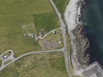 Oblique aerial view centred on the excavated broch and settlement at Old Scatness, Sumburgh, and the visitor attraction, taken from the NE.