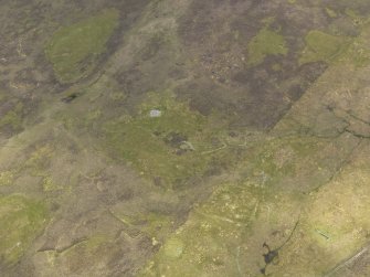 Oblique aerial view of the field system, clearance cairns and building, looking SE.