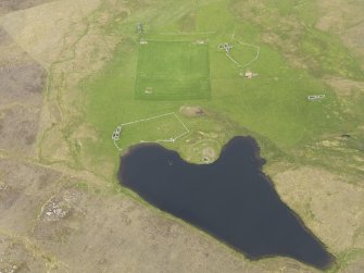 Oblique aerial view of the Loch of Snabrough Broch and the farmsteads, looking NE.