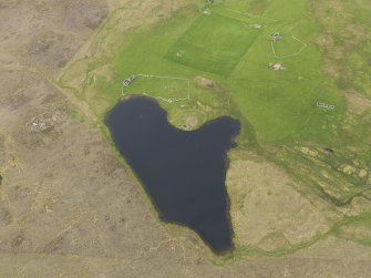 Oblique aerial view of the Loch of Snabrough Broch and the farmsteads, looking N.