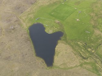 Oblique aerial view of the Loch of Snabrough Broch and the farmsteads, looking NNW.