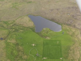 Oblique aerial view of the Loch of Snabrough Broch and the farmsteads, looking SW.