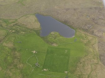 Oblique aerial view of the Loch of Snabrough Broch and the farmsteads, looking SW.