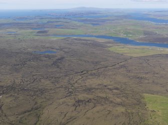 General oblique aerial view of Mid Field, Berrarunies Loch and Hagmark Hill with Effirth and Bixter Voe in the distance, looking N.