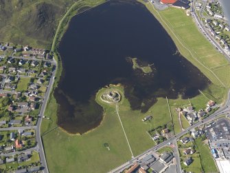 Oblique aerial view centred on the remains of the broch and settlement of Clickhimin, looking NNE.