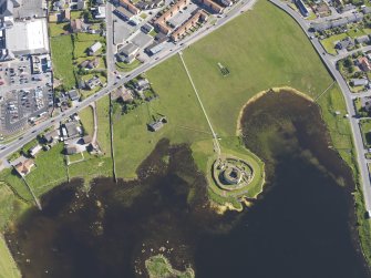 Oblique aerial view centred on the remains of the broch and settlement of Clickhimin, looking SSW.
