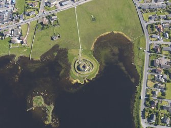 Oblique aerial view centred on the remains of the broch and settlement at Clickhimin, looking S.