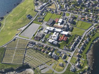 Oblique aerial view centred on Anderson High School, Lerwick, looking NW.