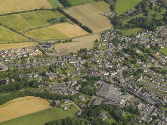 General oblique aerial view of Alyth centred on the Forfar Caprets Mill, taken from the SSW.