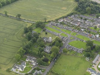 Oblique aerial view of Dalmeny centred on St Cuthbert's Church, taken from the NW.