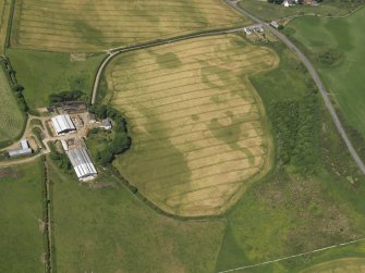 Oblique aerial view of the faint cropmarks of the barrow at Kirkmabreck, taken from the SSE.