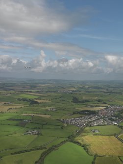 General oblique aerial view of Mossblown with a jet departing Prestwick above, taken from the WSW.
