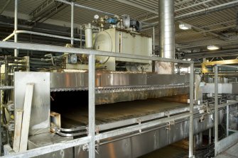 Bottling Plant. Interior. View  from north west of the pasteuriser. Two conveyor lines feed the filled and capped bottles into the two levels of the pasteurisation machine. This view shoes the upper level and the quide rails which feed the bottles onto the accumulation table and onto the conveyor.