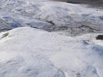 General oblique aerial view of Woden Law fort and linear earthworks in snow, looking W.