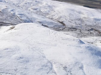 General oblique aerial view of Woden Law fort and linear earthworks in snow, looking WSW.
