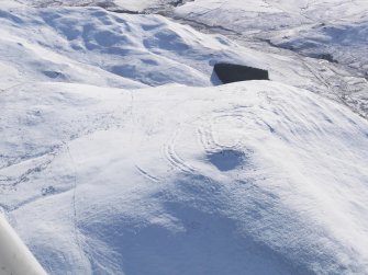 General oblique aerial view of Woden Law fort and linear earthworks in snow, looking, looking SSW.