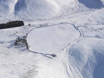 Oblique aerial view of linear earthworks and Roman road in snow, looking SE.