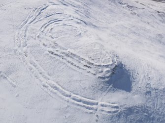 Oblique aerial view of Woden Law fort and linear earthworks in snow, looking SW.