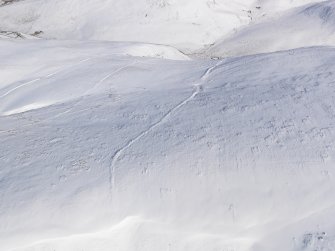 Oblique aerial view of linear earthworks under snow, looking to E.