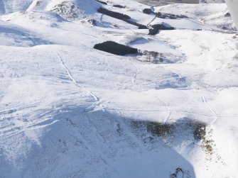 General aerial view of linear earthworks and cairn under snow, looking to W.