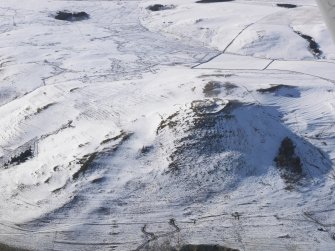 General aerial view of fort, scooped settlement, enclosure, rig and furrow, cultivation terraces and field systems under snow, looking to W.