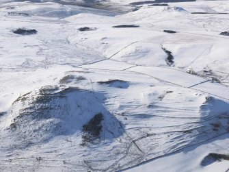 General aerial view of fort, scooped settlement, enclosure, rig and furrow, cultivation terraces and field systems under snow, looking to W.