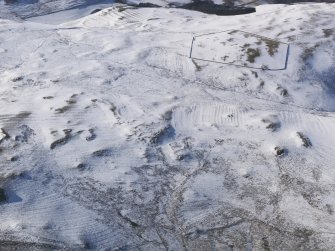 General oblique aerial view of cairn, farmsteads, sheepfold, enclosure and rig and furrow under snow, looking to NW.