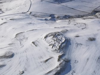 Oblique aerial view of fort, settlement and palisaded enclosure, rig and furrow and field boundaries under snow, looking to W.