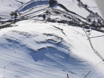 General oblique aerial view of scooped settlement, settlement and cultivation terraces under snow, looking to WSW.