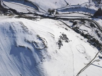 General oblique aerial view of scooped settlement and settlement  under snow, looking to S.