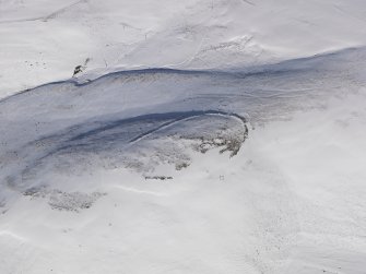 Oblique aerial view of palisaded settlement, enclosure and cord rig under snow, looking to N.