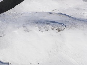 Oblique aerial view of palisaded settlement, enclosure and cord rig under snow, looking to N.