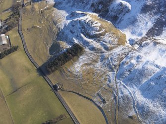 Oblique aerial view of Tinnis Castle and fort,  building, platform, settlement and track, enclosure and cultivation terraces under snow, looking E.