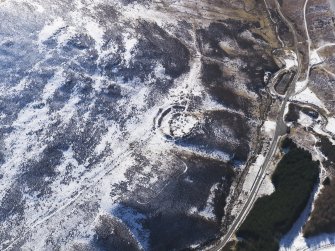 Oblique aerial view of settlement and track under snow, looking SSE.