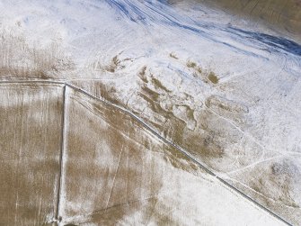 Oblique aerial view of fort, enclosures, settlement, rig, cord rig and cultivation terraces under snow, looking WNW.